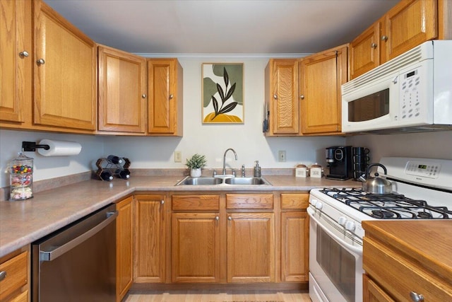 kitchen featuring white appliances, a sink, and brown cabinetry