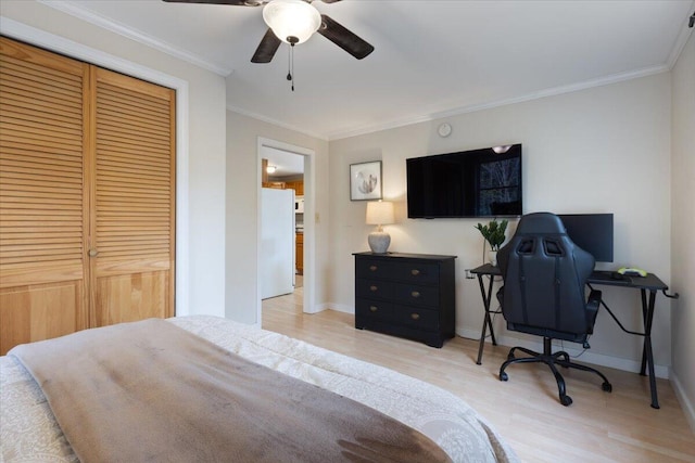 bedroom featuring wood finished floors, freestanding refrigerator, ornamental molding, a closet, and baseboards