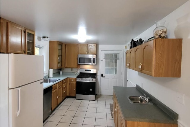 kitchen featuring stainless steel appliances, a sink, light tile patterned floors, and glass insert cabinets