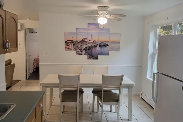 dining space with baseboard heating, ceiling fan, light tile patterned flooring, and baseboards