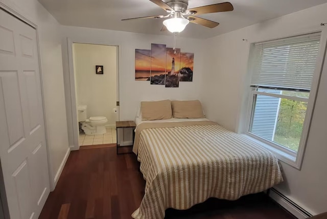bedroom featuring a baseboard radiator, wood finished floors, ensuite bath, baseboards, and ceiling fan