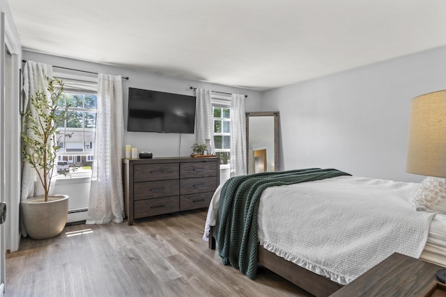 48 Garfield St Unit 7, Saco, ME 04072 - bedroom with a baseboard heating unit, multiple windows, and wood finished floors