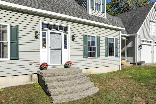 doorway to property with a shingled roof and a lawn