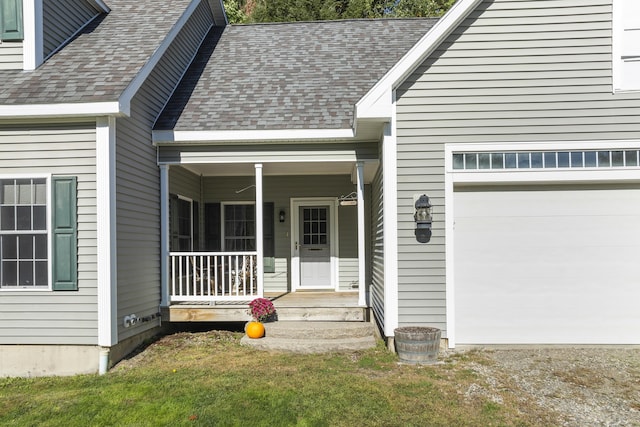 view of exterior entry featuring a porch, a shingled roof, a garage, and driveway