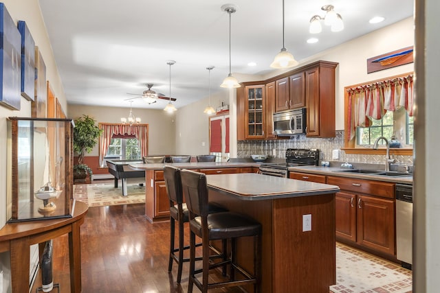 kitchen featuring a peninsula, glass insert cabinets, backsplash, stainless steel appliances, and a sink