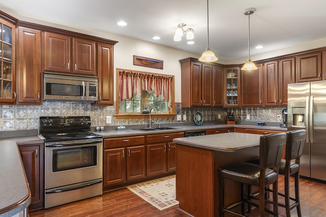 kitchen featuring a kitchen breakfast bar, dark wood-style floors, backsplash, appliances with stainless steel finishes, and a sink