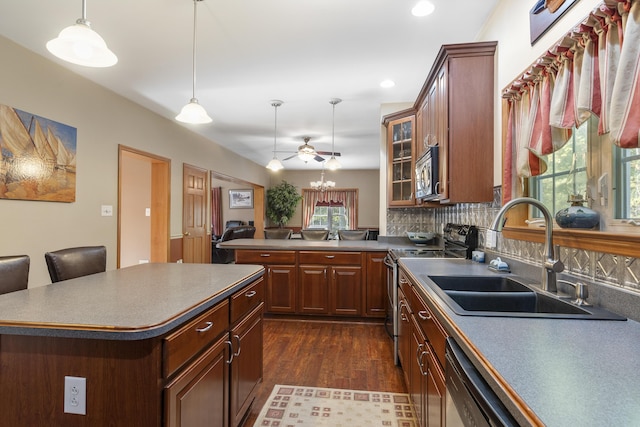 kitchen featuring glass insert cabinets, a sink, appliances with stainless steel finishes, dark wood finished floors, and backsplash