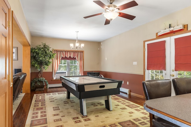 playroom with light wood-style flooring, a baseboard radiator, ceiling fan with notable chandelier, and a baseboard heating unit