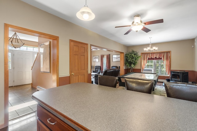 kitchen with decorative light fixtures, open floor plan, a wood stove, baseboard heating, and ceiling fan with notable chandelier