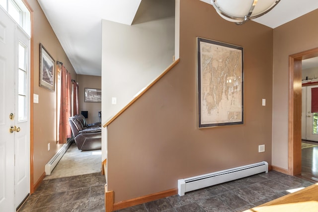 stairway with a baseboard radiator, stone finish floor, and plenty of natural light