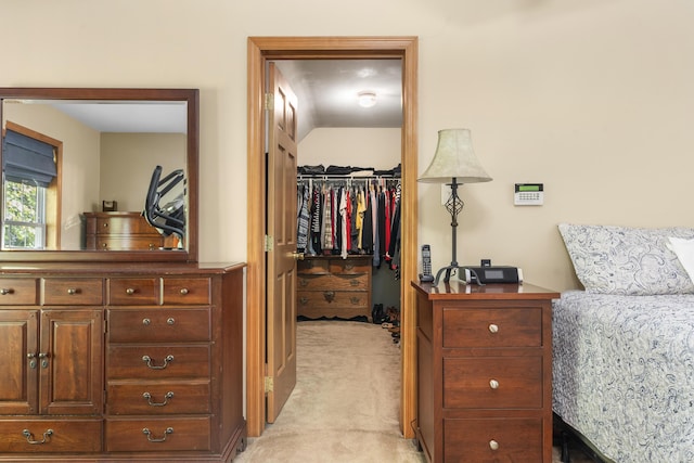 bedroom with light carpet, a closet, and a walk in closet