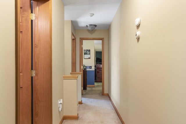 hall with light colored carpet and baseboards