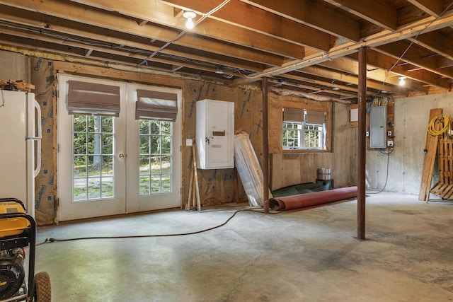 basement with electric panel, french doors, and freestanding refrigerator