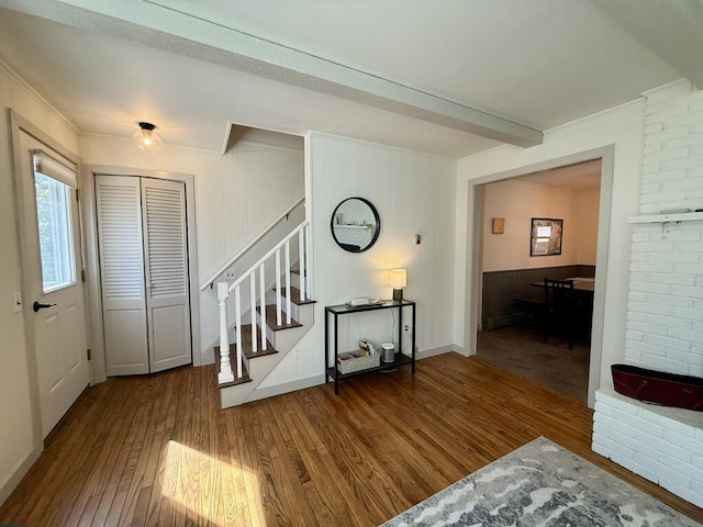 entrance foyer featuring stairs, beamed ceiling, crown molding, and wood finished floors