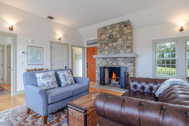 421 Petitmanan Point Rd, Steuben, ME 04680 - living room with lofted ceiling, light wood-style flooring, and a fireplace