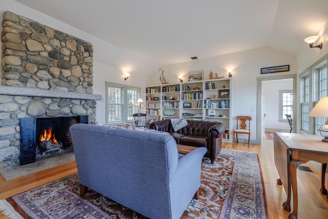 421 Petitmanan Point Rd, Steuben, ME 04680 - living area featuring vaulted ceiling, wood finished floors, healthy amount of natural light, and a fireplace