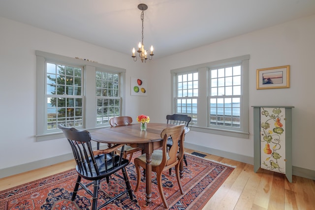 421 Petitmanan Point Rd, Steuben, ME 04680 - dining area with healthy amount of natural light, a chandelier, light wood-style flooring, and baseboards
