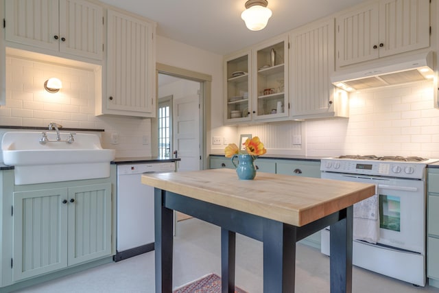 421 Petitmanan Point Rd, Steuben, ME 04680 - kitchen featuring under cabinet range hood, white appliances, a sink, tasteful backsplash, and glass insert cabinets