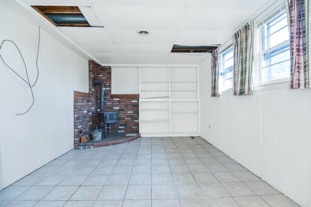 58 Bayview Ter, Wells, ME 04090 - basement with a paneled ceiling, light tile patterned flooring, visible vents, and a wood stove