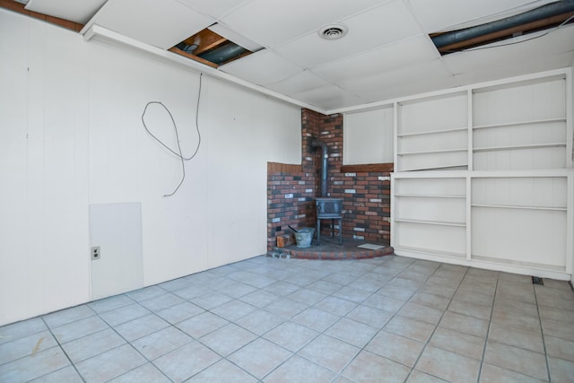 58 Bayview Ter, Wells, ME 04090 - finished below grade area featuring built in features, visible vents, a wood stove, and tile patterned floors