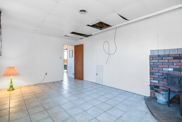 58 Bayview Ter, Wells, ME 04090 - tiled spare room featuring visible vents, a wood stove, and a paneled ceiling