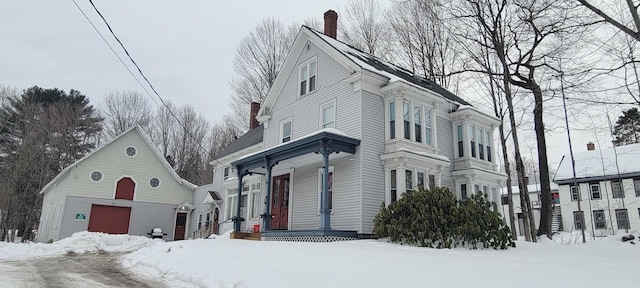 view of snow covered exterior featuring a chimney and a garage