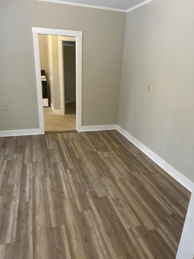 empty room featuring baseboards, wood finished floors, and crown molding