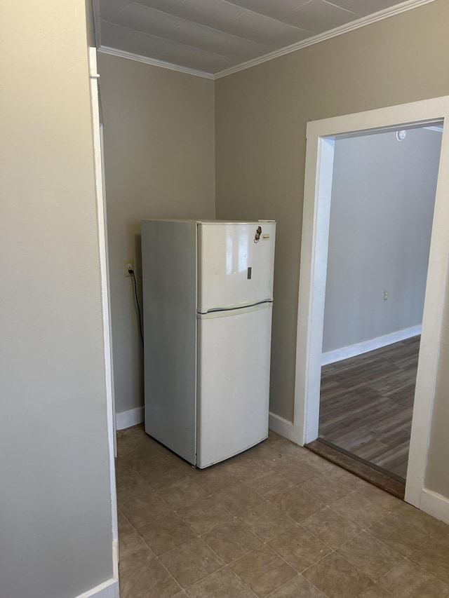 kitchen featuring baseboards, ornamental molding, and freestanding refrigerator