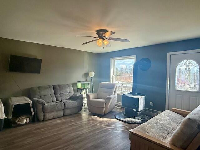 living area with a wealth of natural light, wood finished floors, a wood stove, and ceiling fan