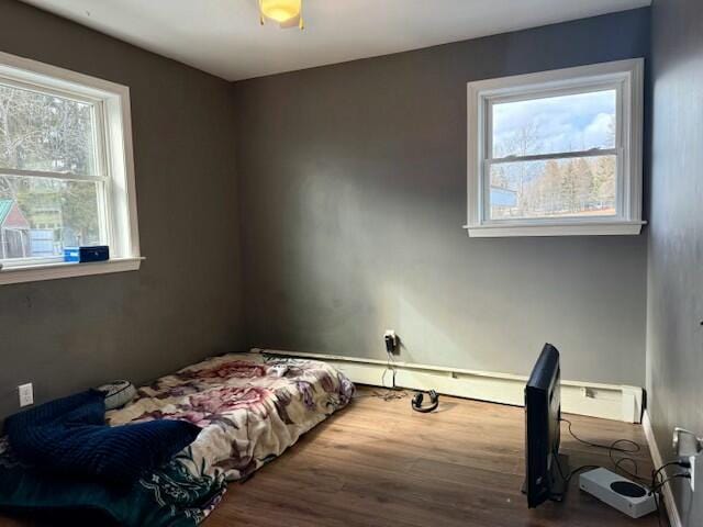 bedroom featuring wood finished floors and a baseboard heating unit