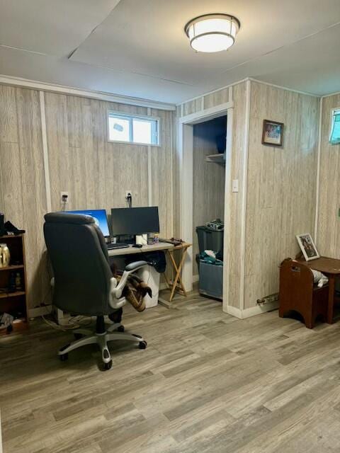 home office featuring a wealth of natural light, wooden walls, and wood finished floors