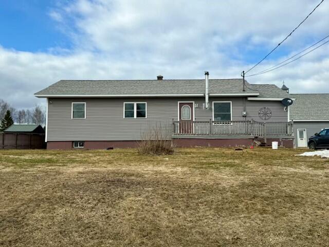 rear view of house featuring a wooden deck and a yard