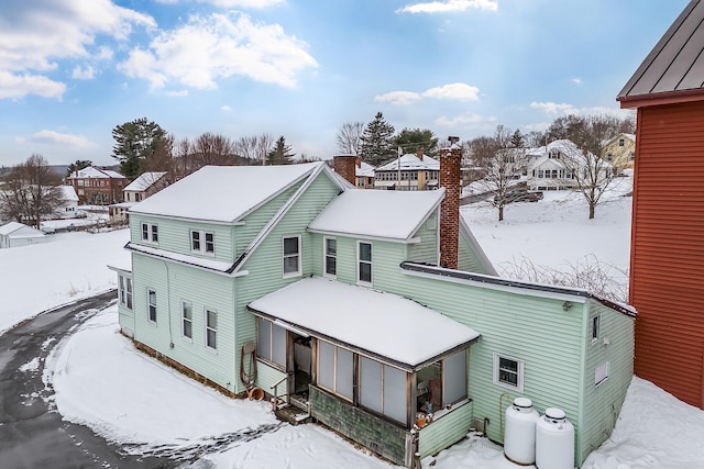 57 Oxford St, Augusta, ME 04330 - snow covered rear of property featuring a residential view, a chimney, and a sunroom