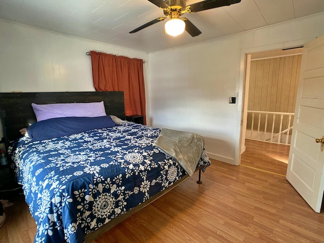 bedroom featuring ornamental molding, light wood-style floors, and ceiling fan