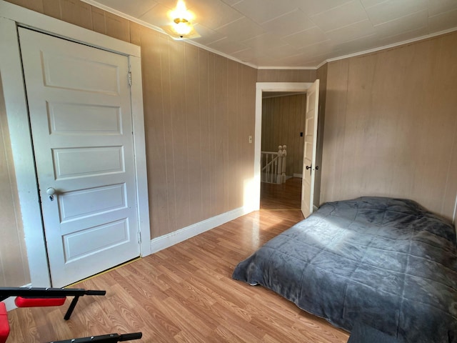 bedroom with baseboards, light wood-type flooring, and crown molding