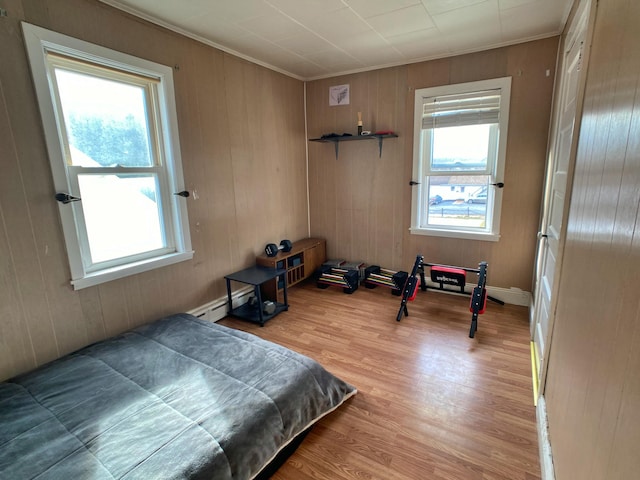 bedroom with crown molding, wood finished floors, and a baseboard heating unit
