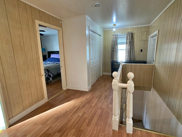 hallway with baseboards, ornamental molding, wood finished floors, and wood walls