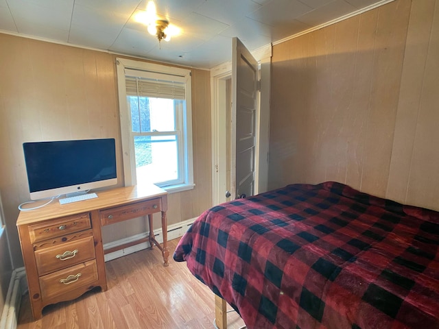 bedroom with light wood-style flooring, a baseboard heating unit, and wood walls