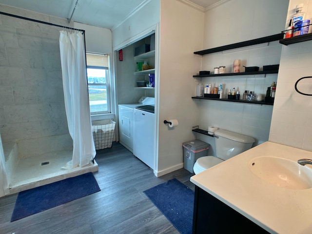 full bath featuring independent washer and dryer, ornamental molding, wood finished floors, vanity, and a stall shower