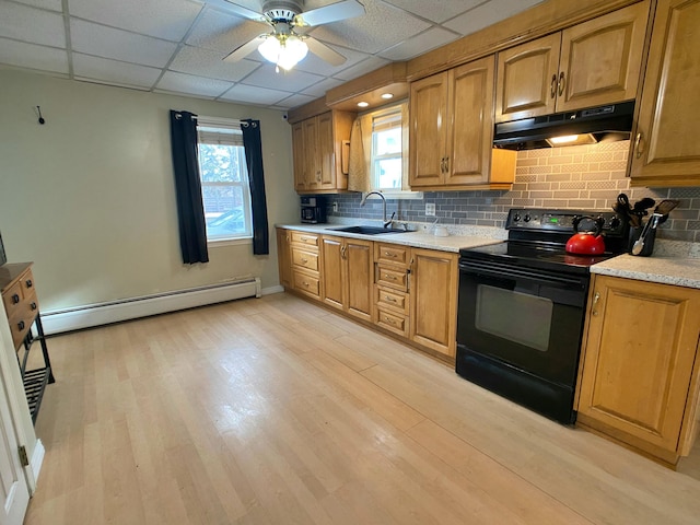 kitchen with under cabinet range hood, a sink, a baseboard heating unit, light wood-style floors, and black electric range