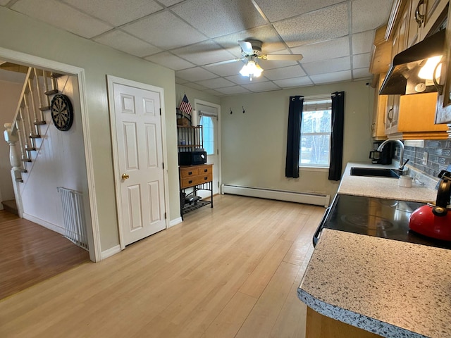 kitchen featuring light countertops, a baseboard heating unit, light wood-type flooring, a sink, and ceiling fan