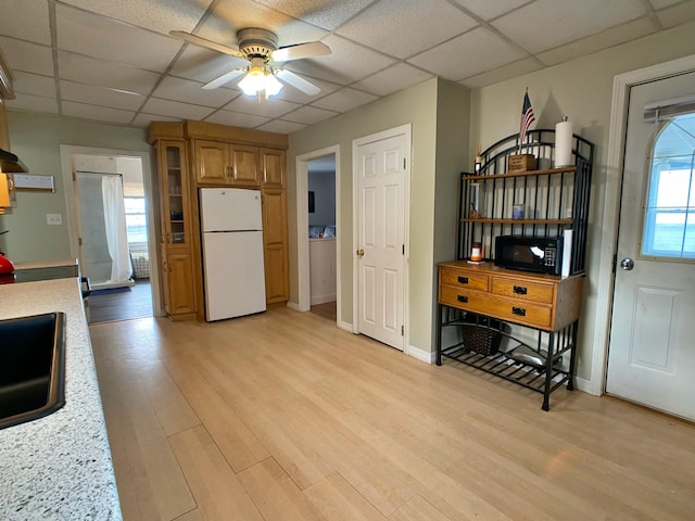 kitchen featuring light countertops, a ceiling fan, a drop ceiling, light wood-style floors, and freestanding refrigerator