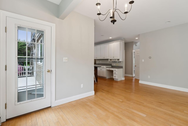 31 Green Trees Dr, Gorham, ME 04038 - kitchen with dark countertops, a chandelier, light wood finished floors, white cabinets, and baseboards