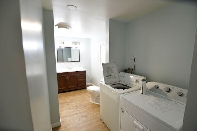laundry area featuring light wood-style flooring, a sink, and independent washer and dryer