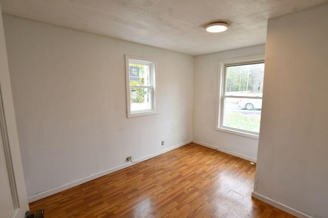 unfurnished room featuring wood finished floors, a textured ceiling, and baseboards