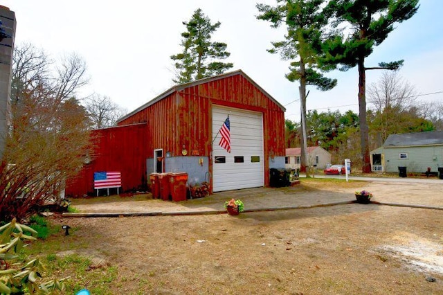 view of outdoor structure with dirt driveway and an outbuilding