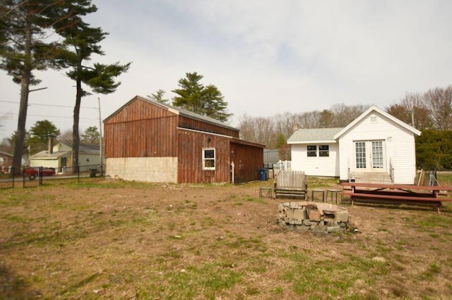 rear view of house with a yard, french doors, an outdoor fire pit, and fence