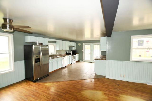 kitchen with wainscoting, stainless steel appliances, a ceiling fan, and dark countertops