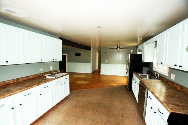 kitchen with dark countertops, dishwashing machine, wainscoting, and a sink