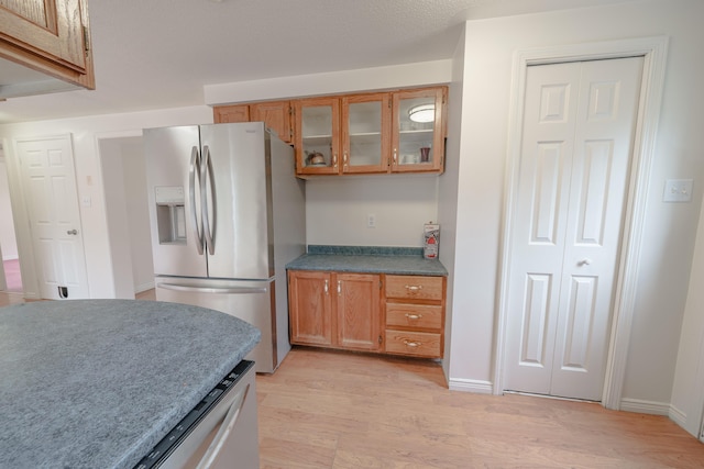 452 Moosehead Trl, Waldo, ME 04915 - kitchen with stainless steel fridge, brown cabinetry, light wood finished floors, glass insert cabinets, and baseboards
